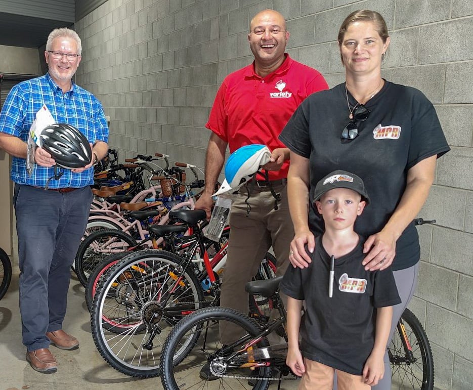 3 adults and a child pose with bikes and helmets.