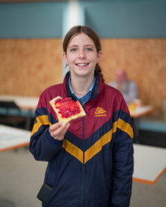 12 year old girl with brown hair in school uniform eating toast and jam